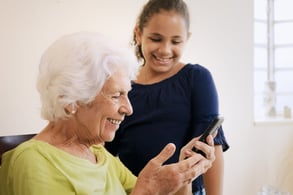 a grandma and a girl looking at a smartphone
